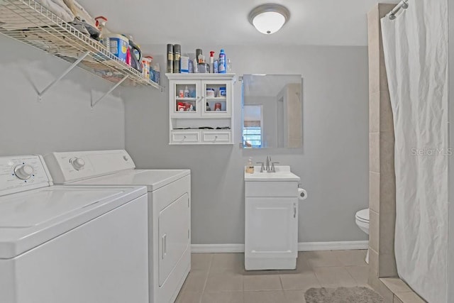 laundry area featuring light tile patterned flooring, laundry area, a sink, baseboards, and washer and clothes dryer