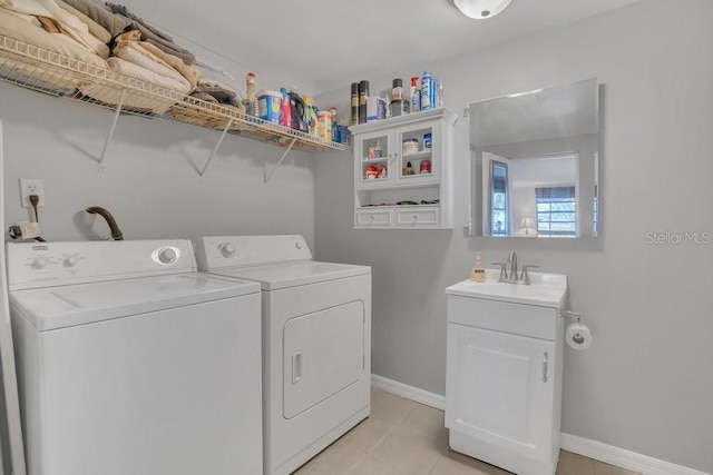 washroom featuring a sink, light tile patterned floors, baseboards, and washer and dryer