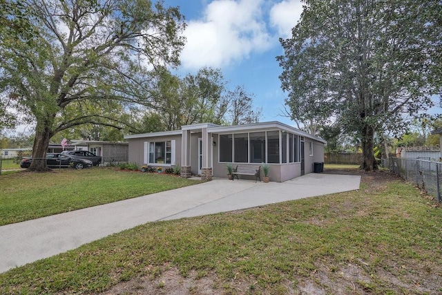 mid-century inspired home featuring a front yard, a sunroom, fence, and driveway