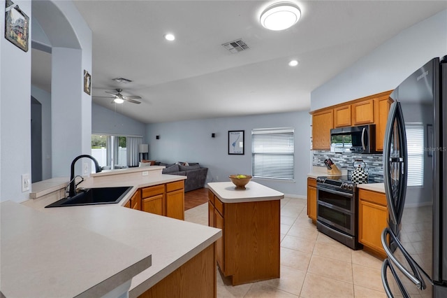 kitchen with freestanding refrigerator, a peninsula, light countertops, double oven range, and a sink