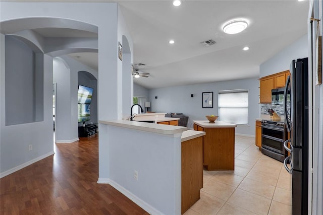 kitchen with visible vents, range with two ovens, a center island, a peninsula, and light countertops