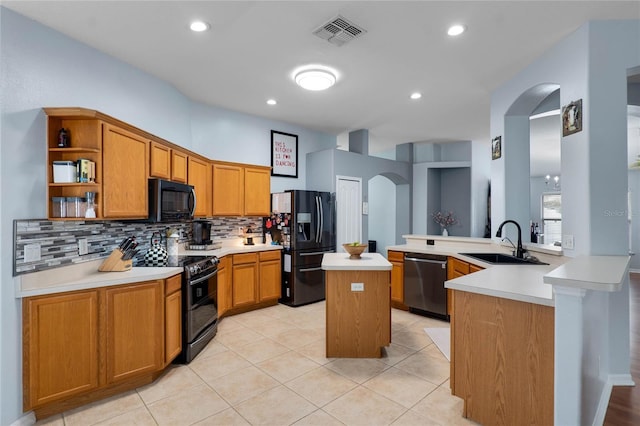 kitchen with arched walkways, light countertops, a sink, a peninsula, and black appliances