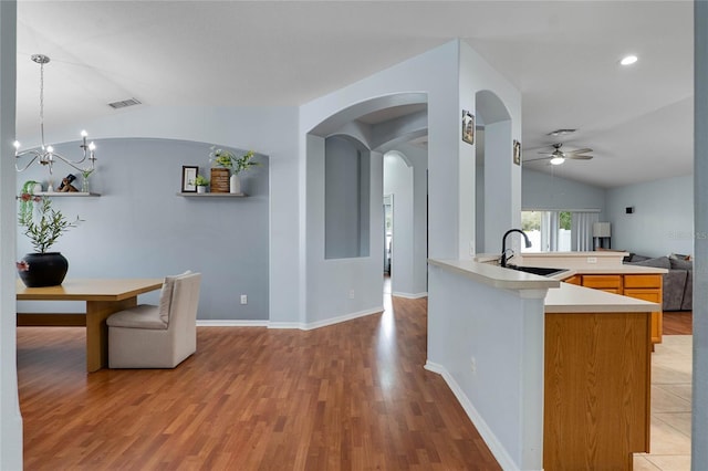 kitchen with decorative light fixtures, lofted ceiling, light countertops, visible vents, and a sink