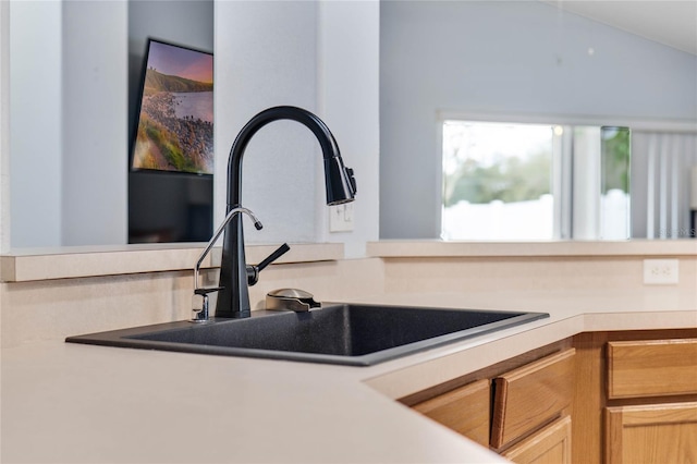 kitchen featuring vaulted ceiling, light brown cabinets, light countertops, and a sink