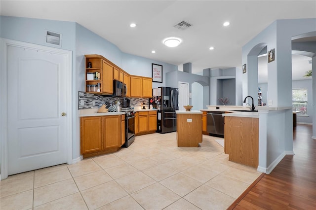 kitchen with arched walkways, light countertops, visible vents, and black appliances