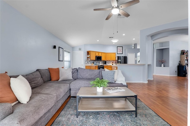 living area featuring arched walkways, lofted ceiling, recessed lighting, dark wood-style flooring, and a ceiling fan