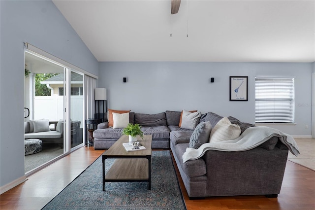 living area featuring vaulted ceiling, baseboards, wood finished floors, and a healthy amount of sunlight