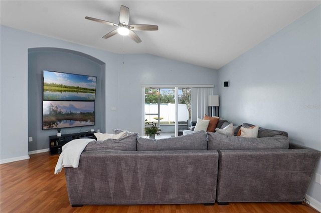 living room featuring ceiling fan, vaulted ceiling, baseboards, and wood finished floors