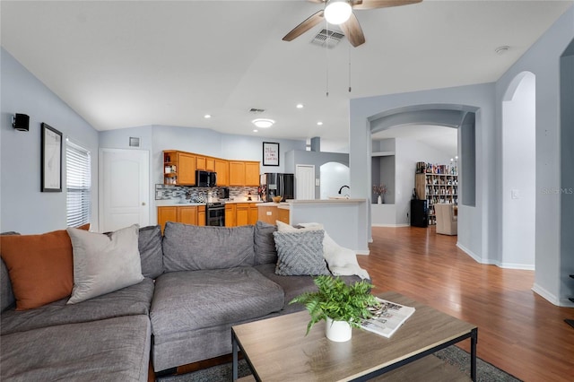 living room featuring arched walkways, visible vents, ceiling fan, and light wood finished floors