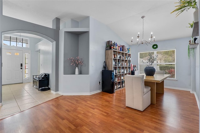 office featuring light wood-type flooring, a notable chandelier, arched walkways, and baseboards