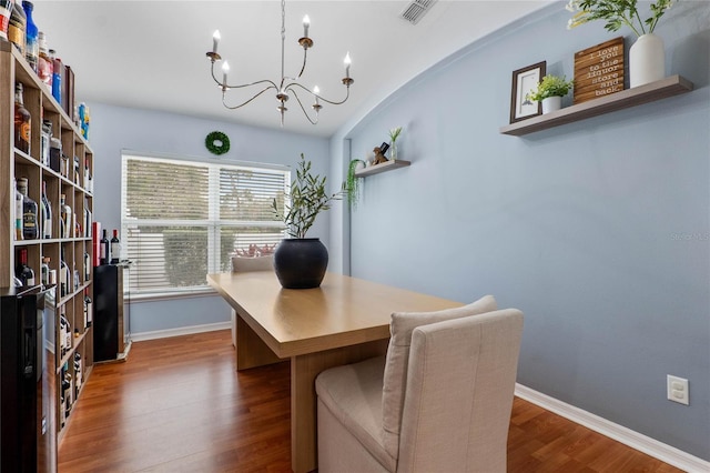 office space featuring a notable chandelier, dark wood-type flooring, visible vents, and baseboards