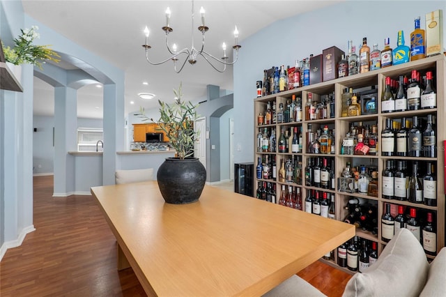 office area with arched walkways, lofted ceiling, a chandelier, wood finished floors, and baseboards