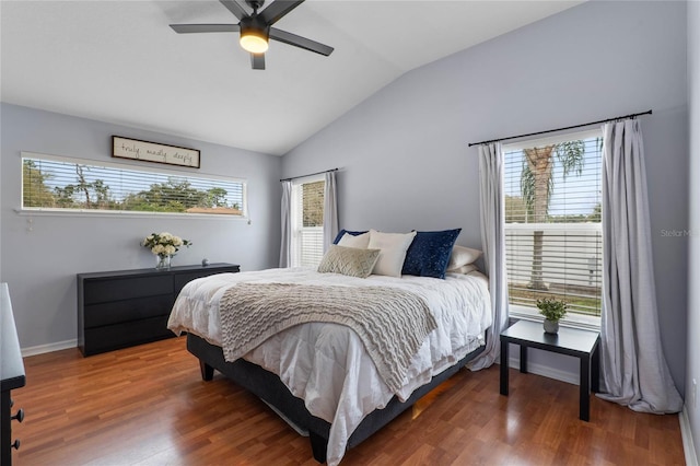 bedroom with vaulted ceiling, multiple windows, dark wood-style floors, and a ceiling fan