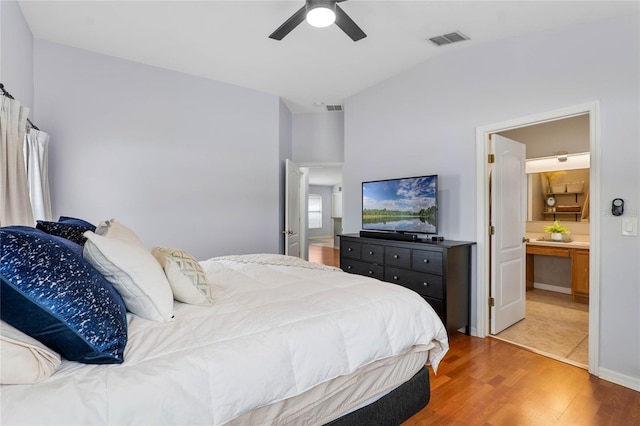 bedroom featuring a ceiling fan, visible vents, ensuite bathroom, and wood finished floors