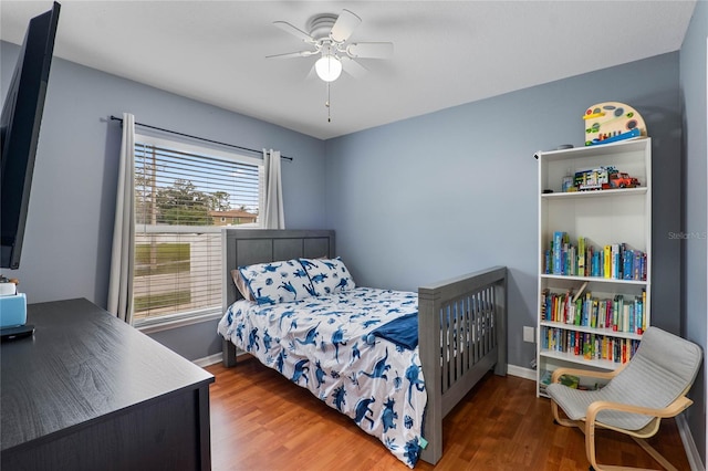 bedroom with ceiling fan, dark wood-type flooring, and baseboards