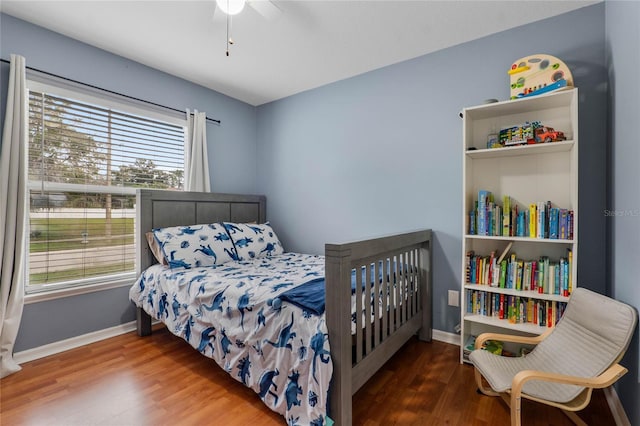 bedroom featuring ceiling fan, baseboards, and wood finished floors