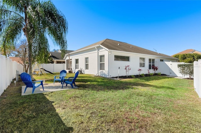 rear view of house with a fenced backyard, a lawn, a gate, stucco siding, and a patio area