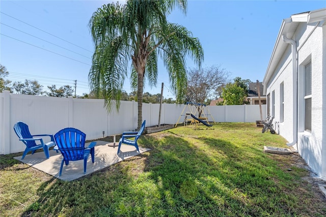 view of yard with a fenced backyard, a patio, and a playground