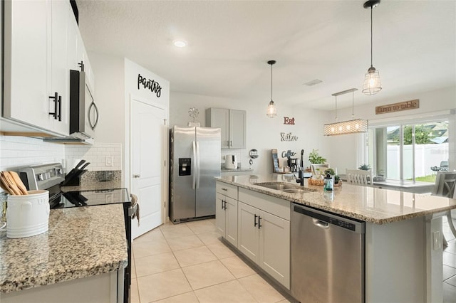 kitchen with appliances with stainless steel finishes, a kitchen island with sink, and decorative light fixtures