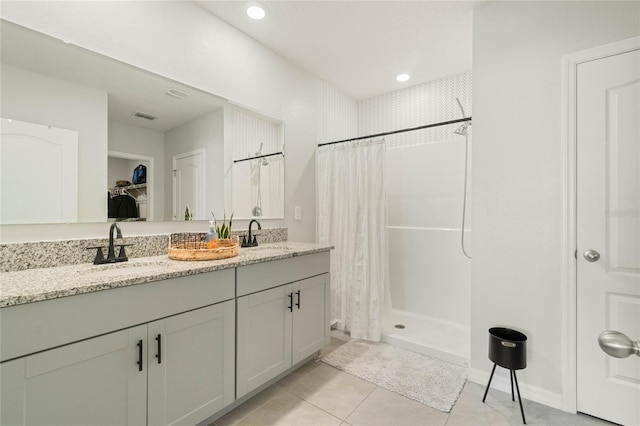 bathroom featuring a stall shower, tile patterned flooring, a walk in closet, and a sink