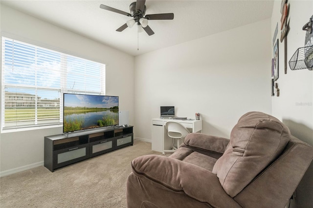 living area featuring light carpet, baseboards, and a ceiling fan