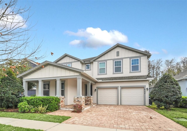 view of front of house featuring a porch, an attached garage, a shingled roof, decorative driveway, and board and batten siding