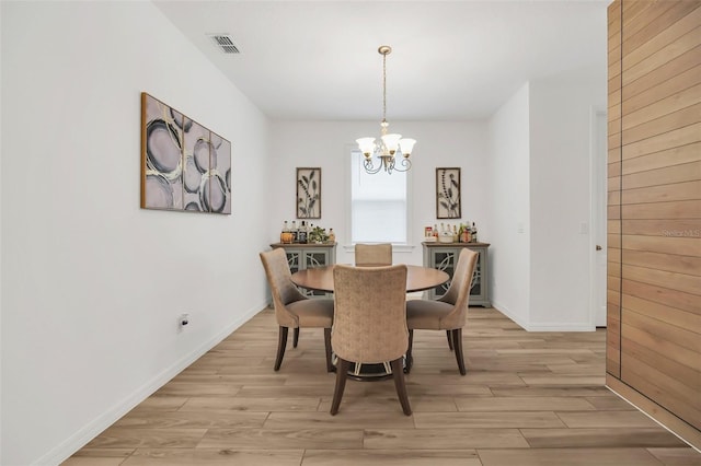 dining area with light wood-type flooring, visible vents, a notable chandelier, and baseboards