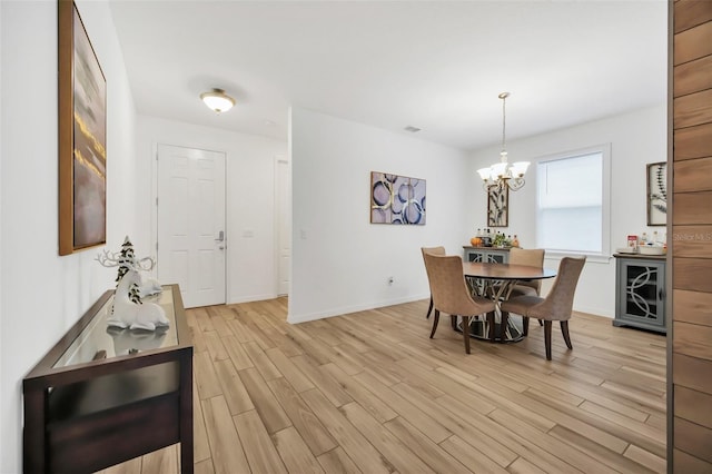 dining space with light wood-style floors, baseboards, and an inviting chandelier