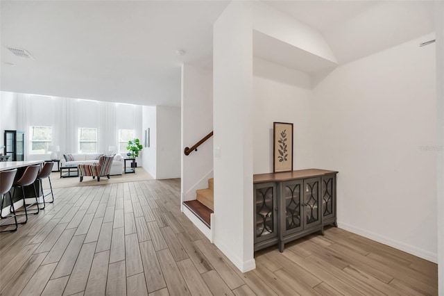 interior space with visible vents, light wood-style flooring, baseboards, and stairs