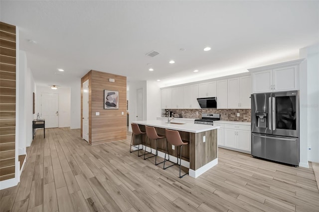 kitchen featuring an island with sink, white cabinetry, appliances with stainless steel finishes, and light countertops