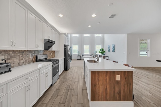 kitchen with a center island with sink, appliances with stainless steel finishes, open floor plan, and light countertops