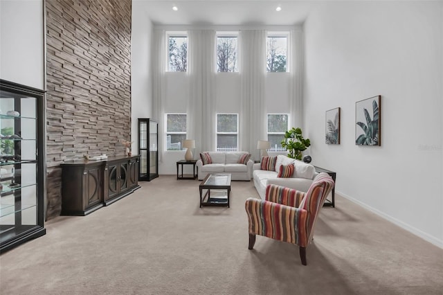 living room featuring baseboards, a high ceiling, recessed lighting, and light colored carpet