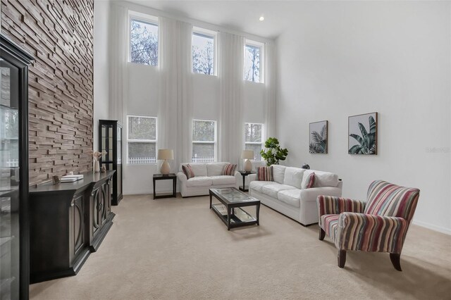 living room with baseboards, a high ceiling, and light colored carpet