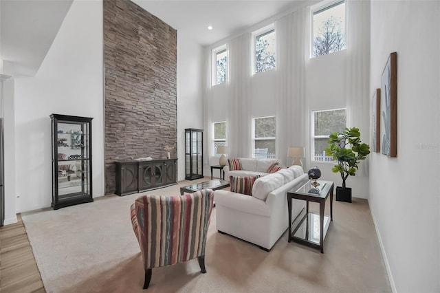 living area featuring a towering ceiling, a fireplace, and baseboards