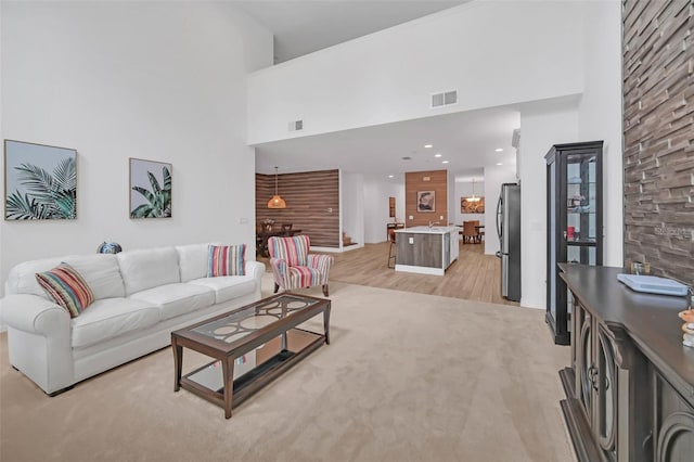 living area featuring light wood finished floors, a high ceiling, and visible vents