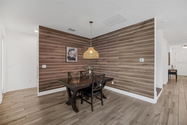 dining area with an accent wall, wood finished floors, and baseboards