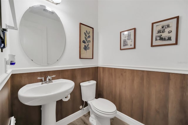 bathroom with a wainscoted wall and toilet