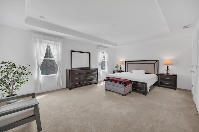 bedroom featuring a raised ceiling, visible vents, and light carpet