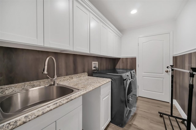 laundry area with cabinet space, light wood-style floors, separate washer and dryer, a sink, and recessed lighting