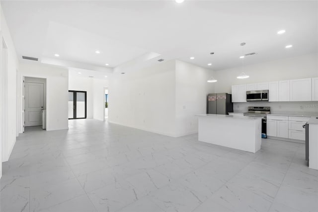 kitchen featuring white cabinets, a kitchen island, appliances with stainless steel finishes, open floor plan, and light countertops