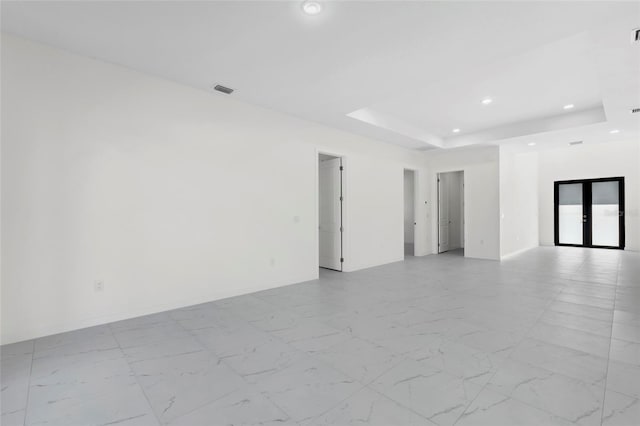 unfurnished room featuring marble finish floor, french doors, a raised ceiling, and recessed lighting