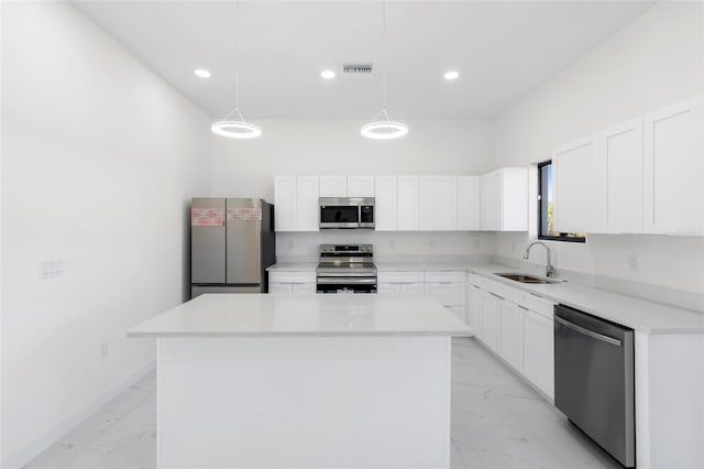 kitchen featuring stainless steel appliances, hanging light fixtures, a kitchen island, and light countertops