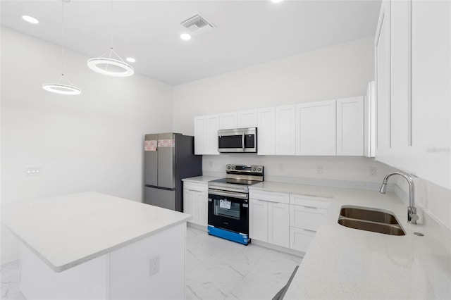 kitchen with stainless steel appliances, pendant lighting, light countertops, and white cabinetry