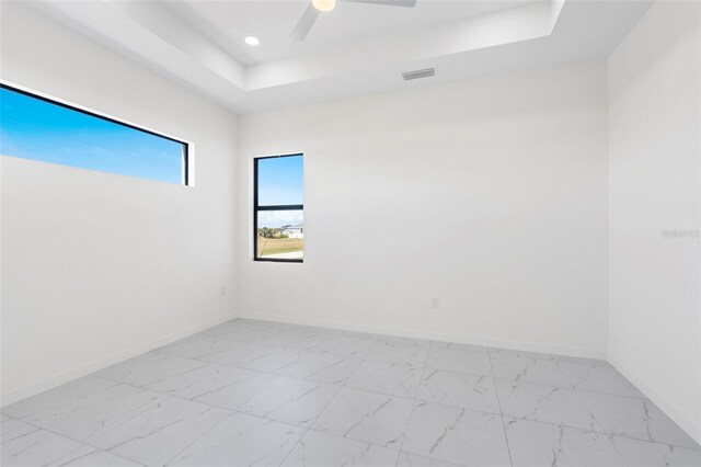 empty room with recessed lighting, a ceiling fan, baseboards, marble finish floor, and a tray ceiling