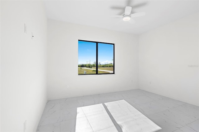 empty room featuring a ceiling fan and marble finish floor