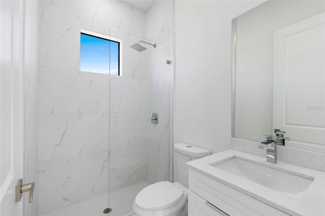 bathroom featuring toilet, a marble finish shower, and vanity