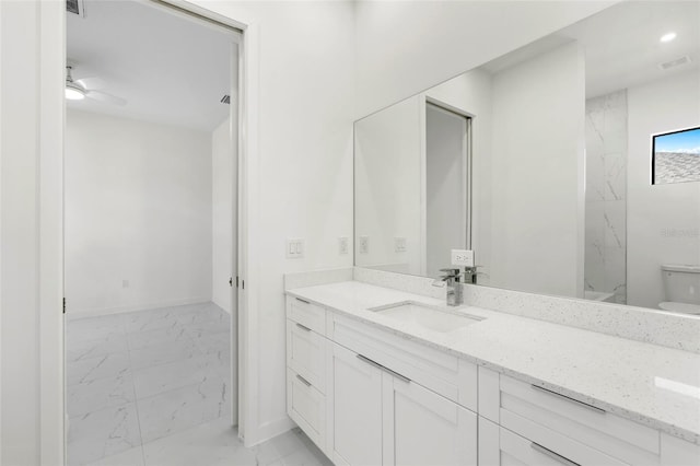 bathroom featuring toilet, visible vents, vanity, baseboards, and marble finish floor