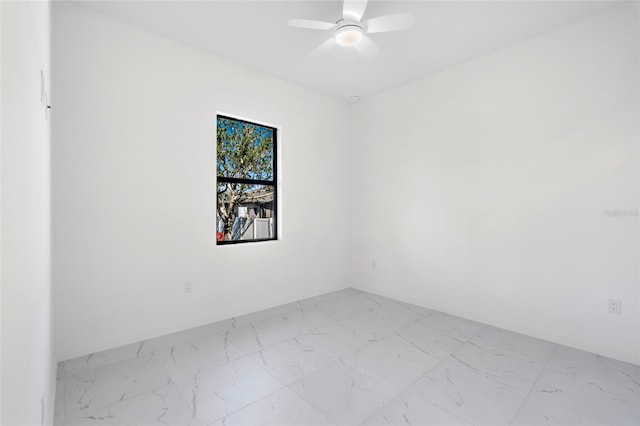 spare room featuring a ceiling fan and marble finish floor