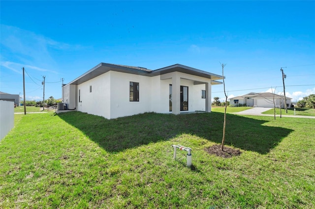 view of front of house featuring cooling unit, a front lawn, and stucco siding