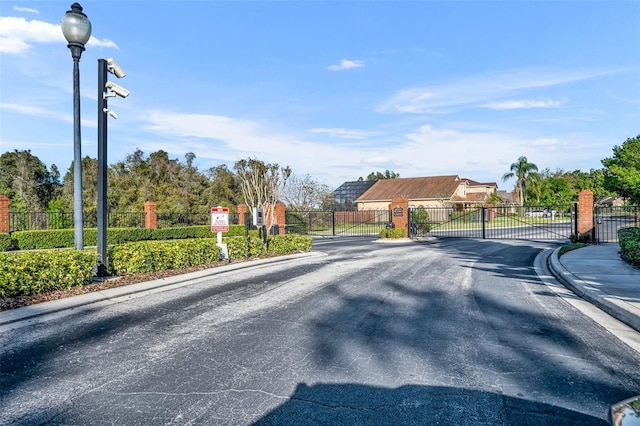 view of street with street lighting, a gate, a gated entry, and curbs